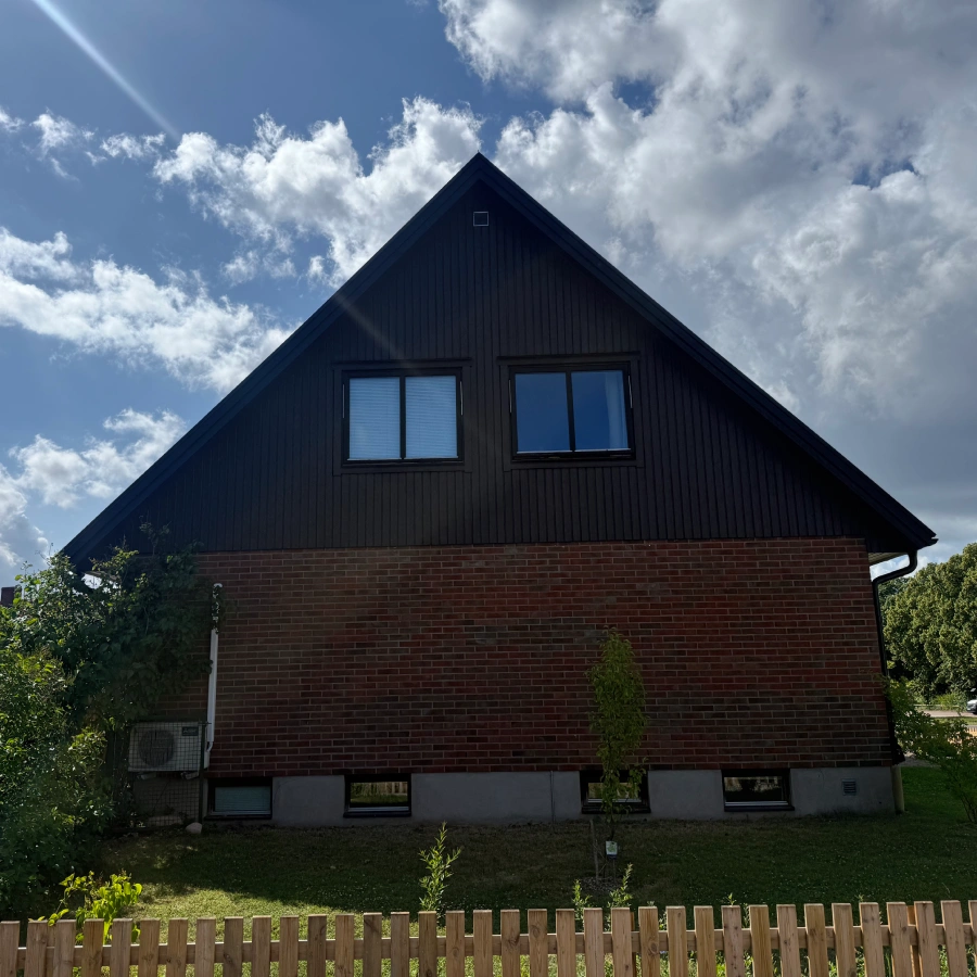 Gavelsida på brunt tegelhus efter ett takbyte och fasadrenovering