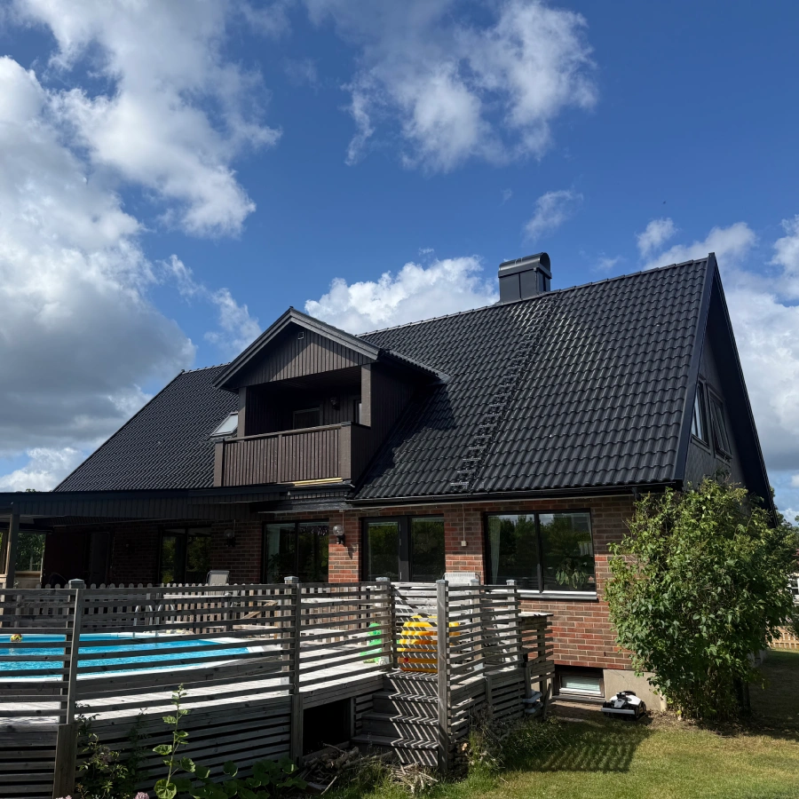 Brunt tegelhus med balkong på baksidan, efter ett takbyte och fasadrenovering