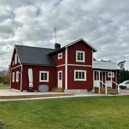 Rött hus med vita knutar efter fasadbyte och takbyte.