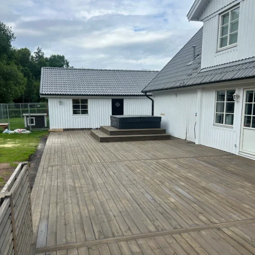 Trädäck på baksidan av ett vitt trähus