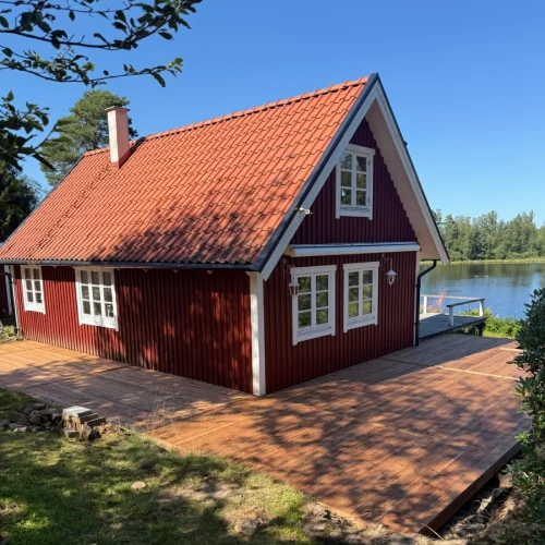 Tralldäck vid ett rött hus nere vid en sjö