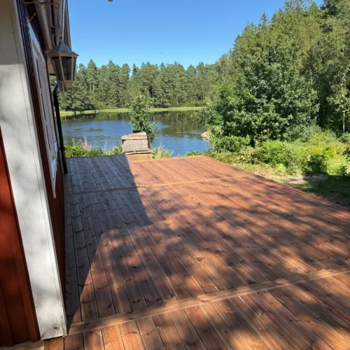 Tralldäck vid ett rött hus nere med utsikt över en sjö