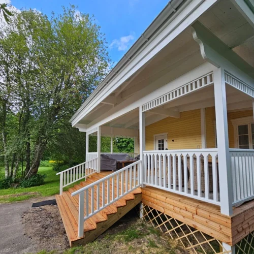 Veranda med trappa vid ett gult hus